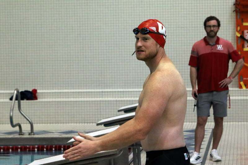 a man in a swim cap and goggles standing next to a swimming pool