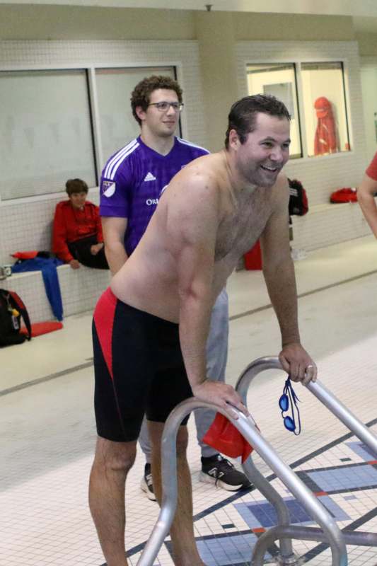 a man holding a ladder in a swimming pool