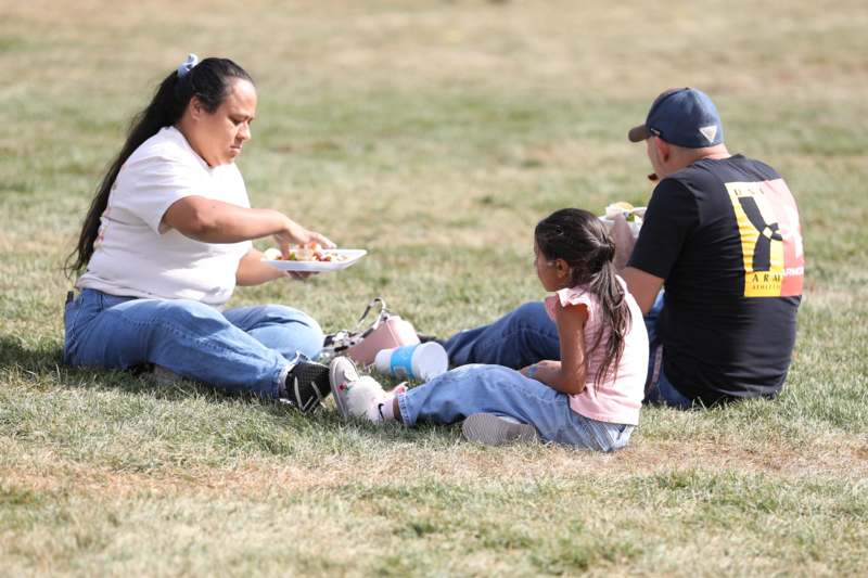 a woman and a girl sitting on the ground eating food
