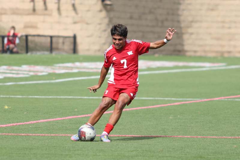 a man in a red uniform kicking a football ball