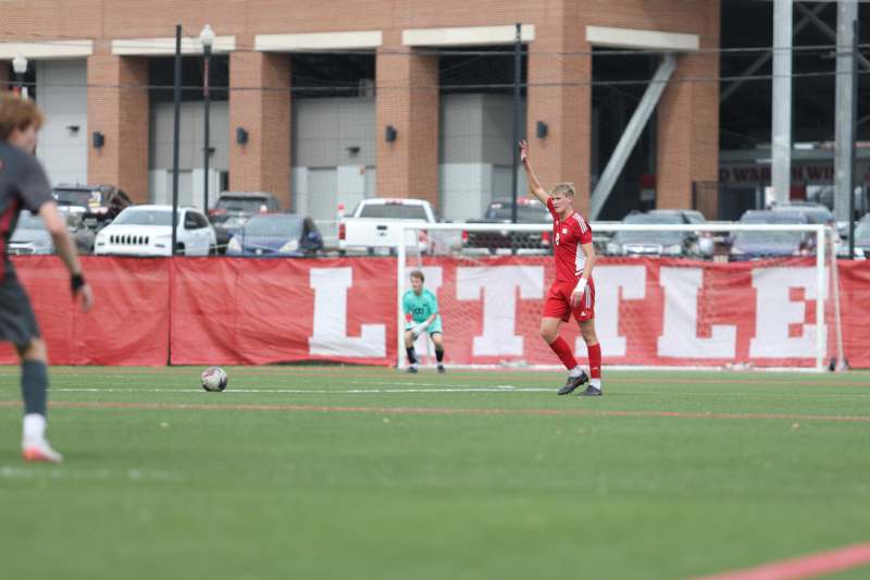 a man in a red uniform on a field with a football ball