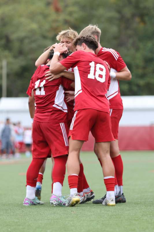 a group of men in red uniforms huddling on a field