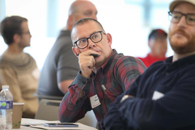 a man with glasses and a pen in his mouth