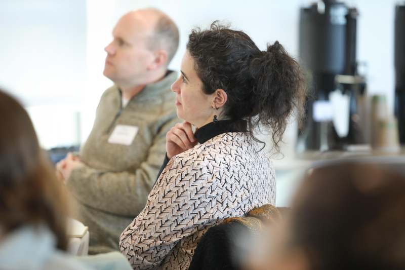 a woman sitting in a room with a man in the background