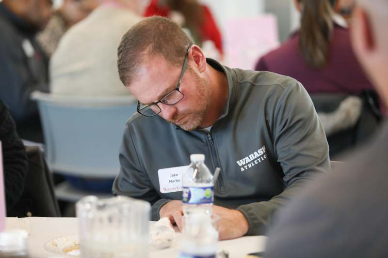 a man wearing glasses and a name tag sitting at a table