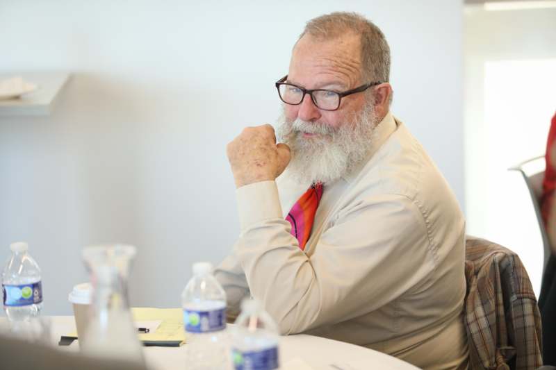 a man with a beard and glasses sitting at a table