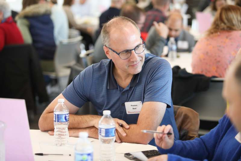 a man sitting at a table with water bottles and a pen