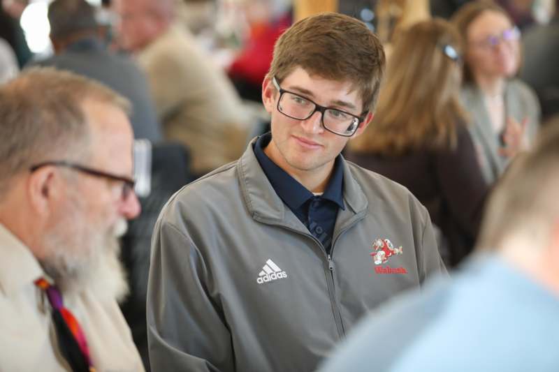 a man wearing glasses and a grey jacket