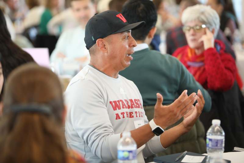 a man in a black hat talking to a group of people