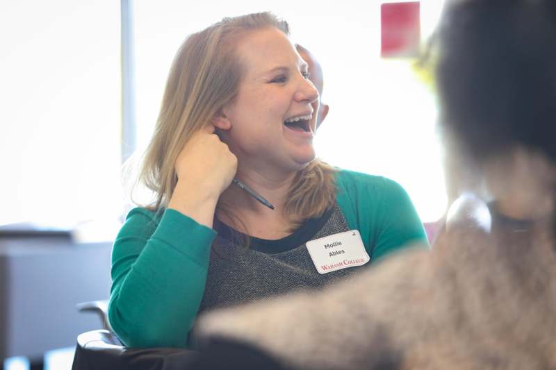 a woman laughing with a pen