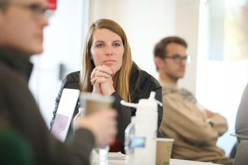 a woman sitting at a table with her hands folded