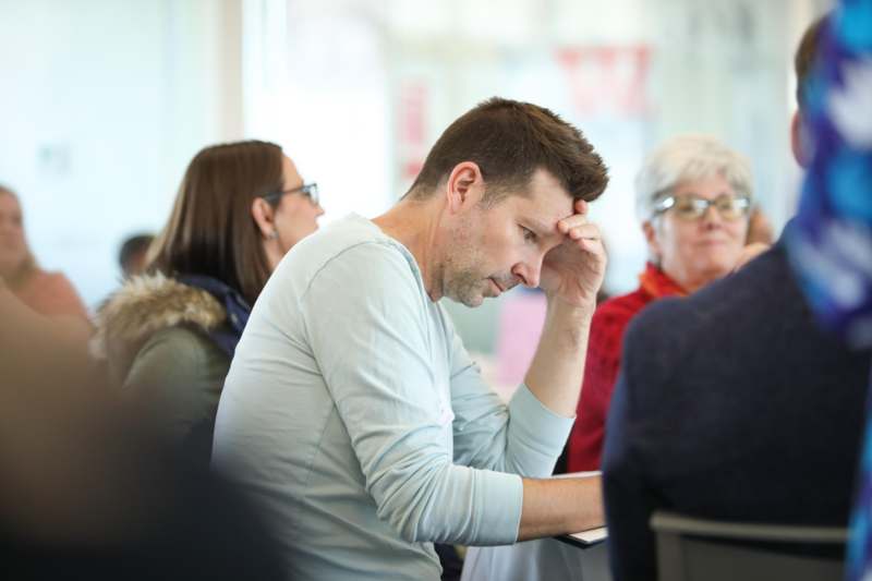a man sitting in a room with his head in his hand