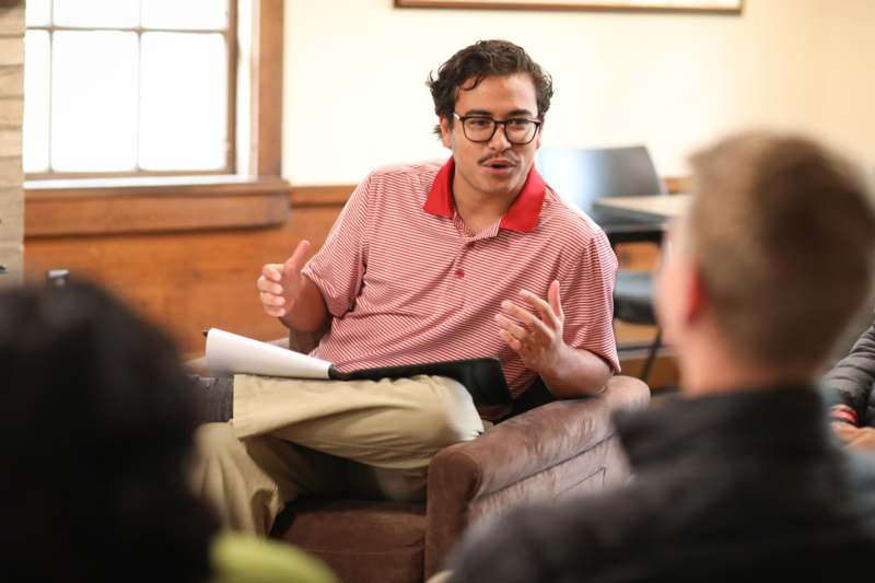 a man sitting in a chair with a clipboard and a man holding a book