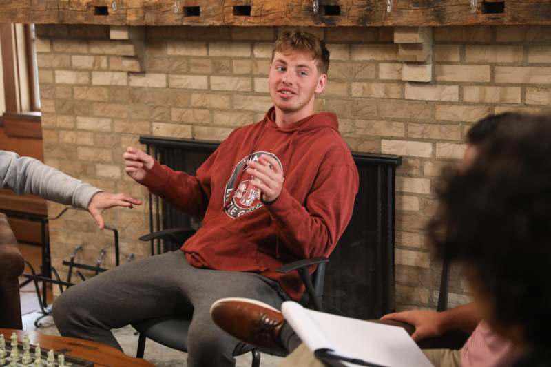 a man sitting in a chair with a man in a red sweatshirt
