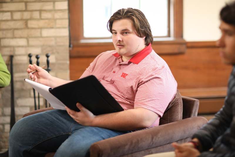 a man sitting in a chair holding a book and pen