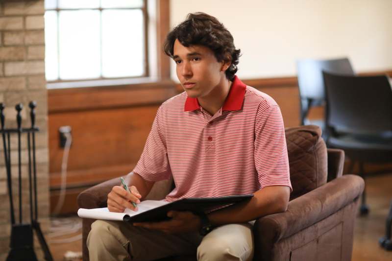 a man sitting in a chair holding a book and pen