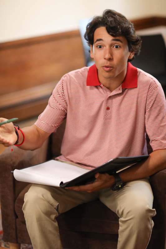 a man sitting in a chair holding a book and a pen