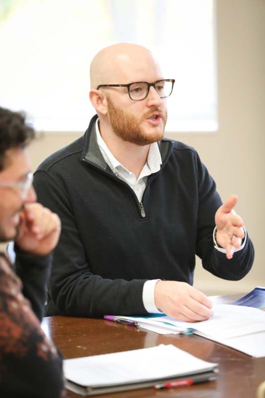 a man in glasses talking to another man