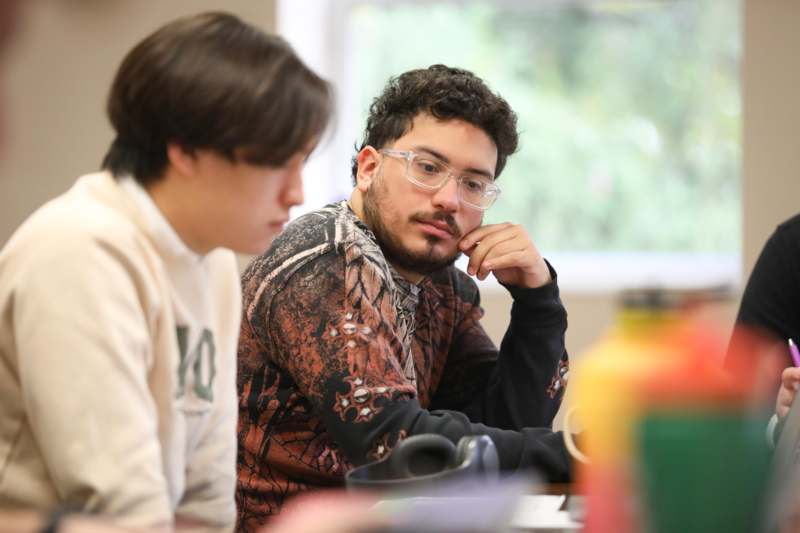 a man sitting at a table with another man in glasses