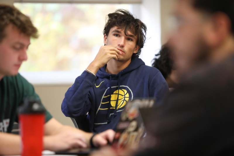 a man sitting at a table with his hand on his chin