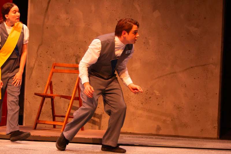 a man in a vest and tie on a stage