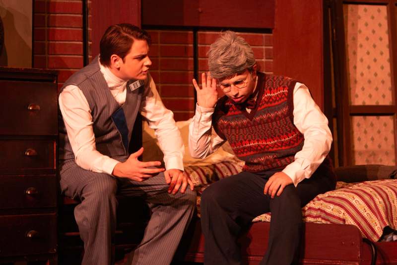 two men sitting on a bed