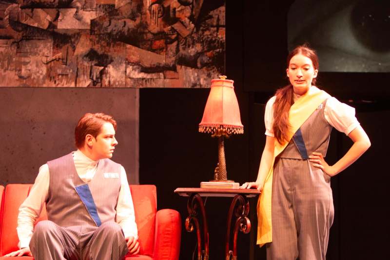 a man and woman in overalls standing next to a table