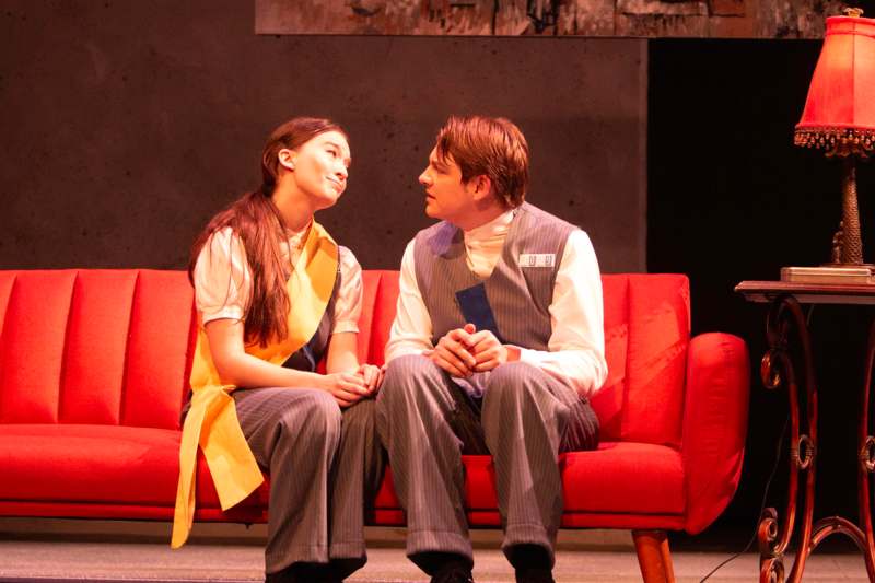 a man and woman sitting on a red couch