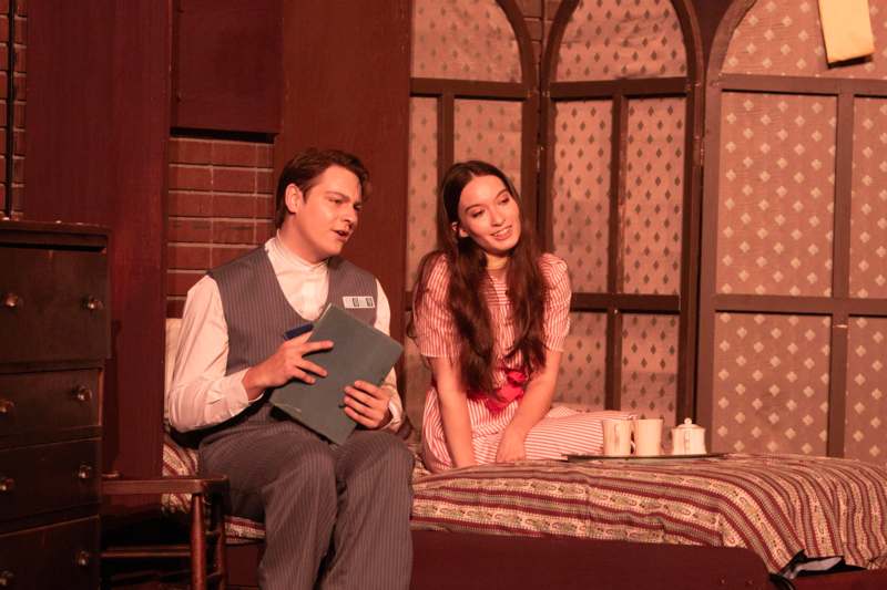 a man and woman sitting on a bed