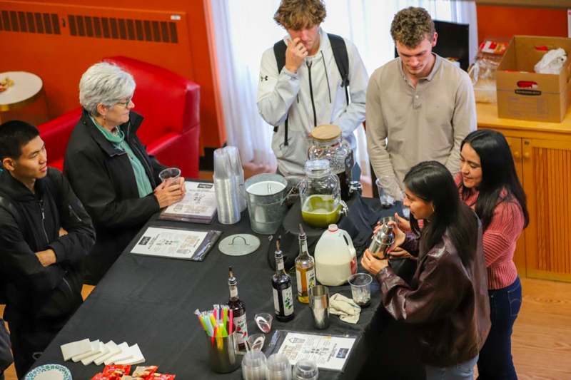 a group of people standing around a table with drinks