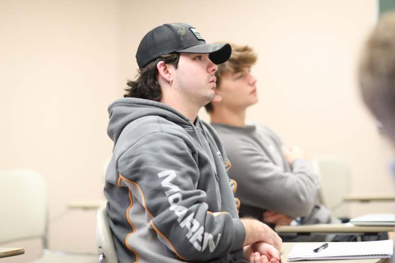 a man in a black hat sitting in a classroom