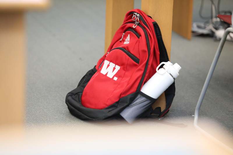 a red backpack with a white water bottle on the side