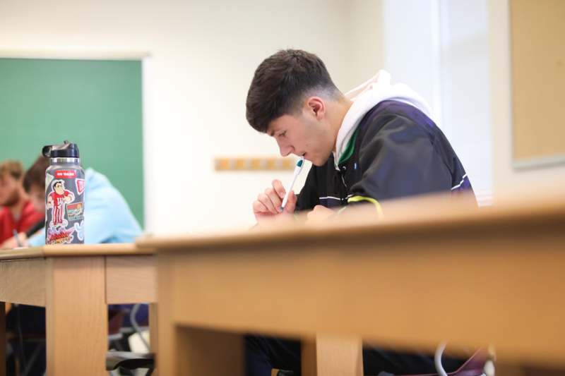 a man sitting at desks in a classroom