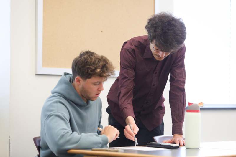 a man standing next to a man looking at a paper