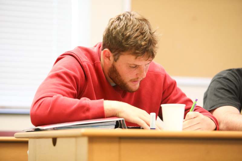 a man in a red shirt writing on a book