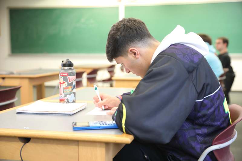 a man sitting at a desk writing on a piece of paper