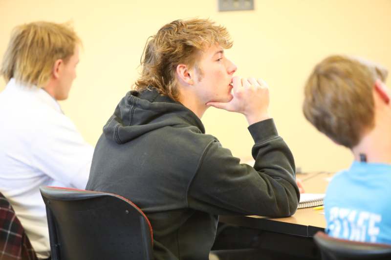 a man sitting at a table with his hand on his chin