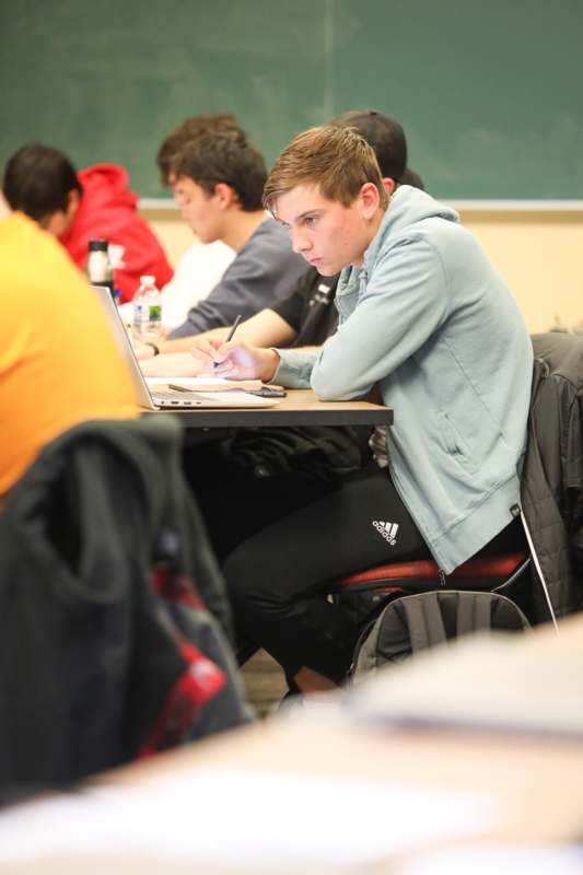 a man sitting at a desk writing on a paper