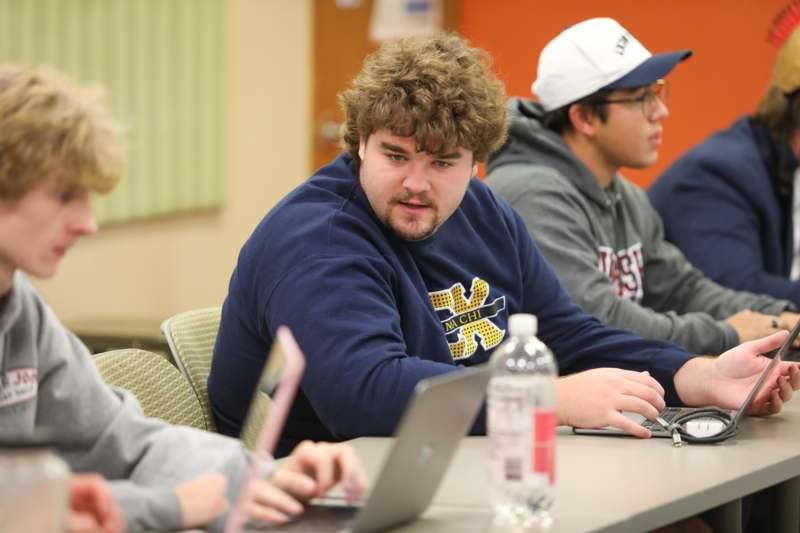 a group of people sitting at a table with laptops