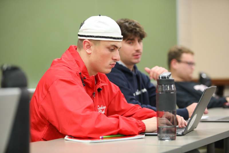 a group of men sitting at a table looking at a laptop