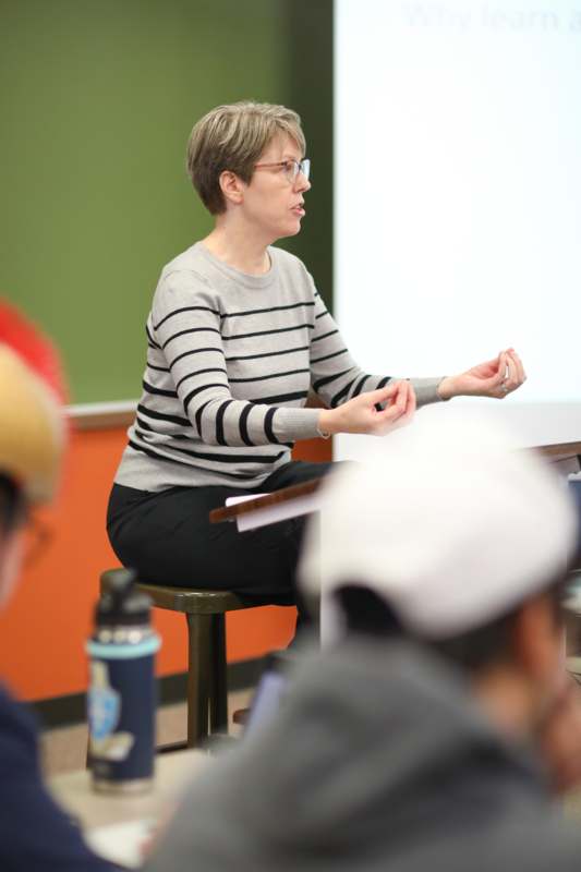 a woman sitting in a chair in front of a green board