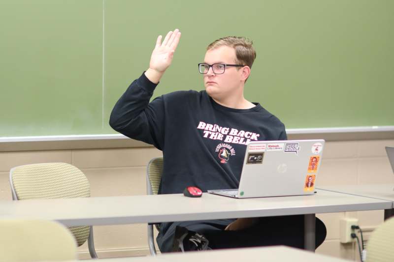a man sitting at a table with his hand raised