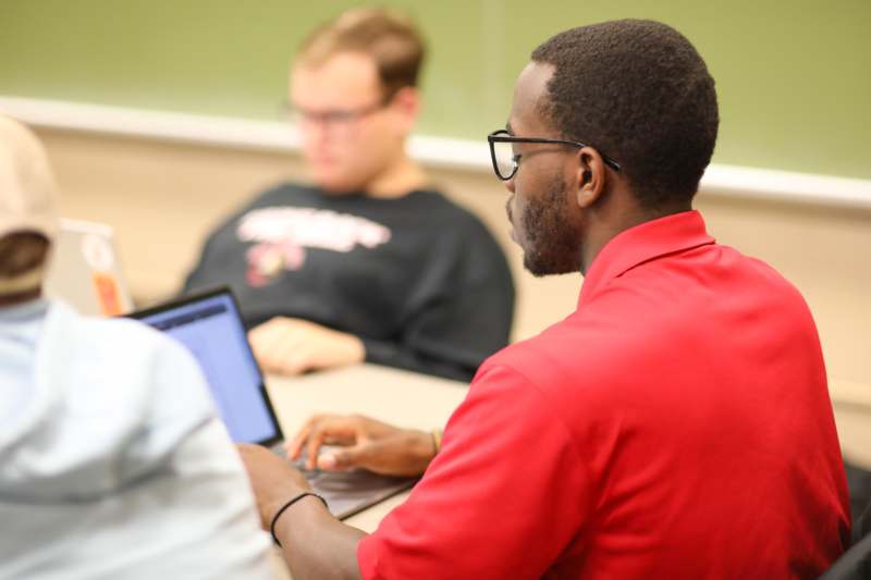 a man in a red shirt using a laptop