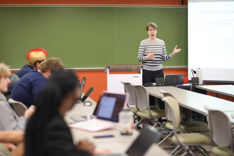 a woman standing in front of a green board