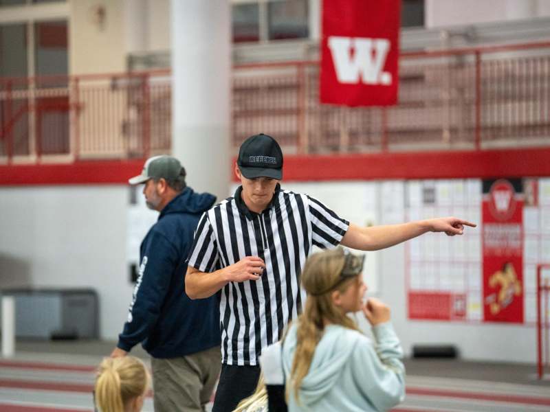 a man in a black and white striped shirt pointing to a group of people