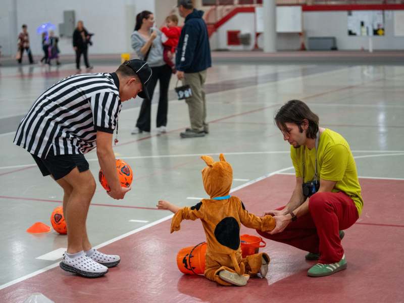 a man in a garment holding a child in a basketball court
