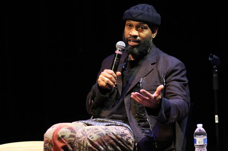 a man sitting on a stage holding a microphone