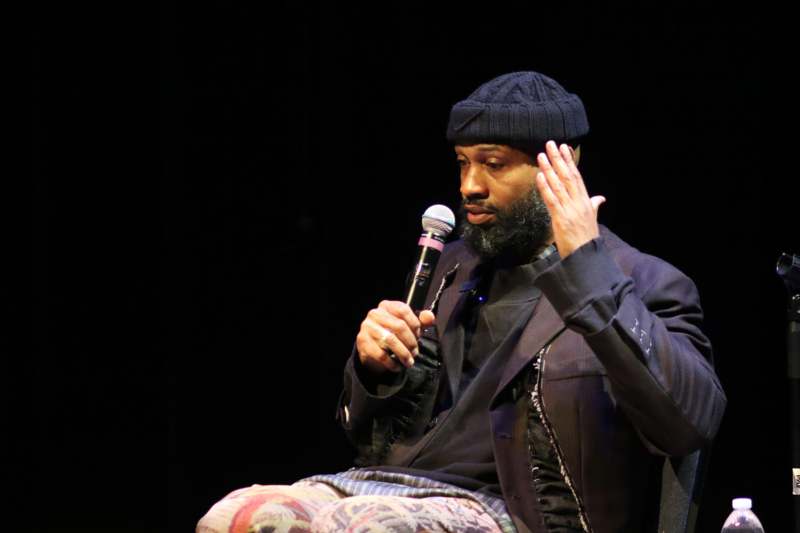 a man sitting on a stage holding a microphone