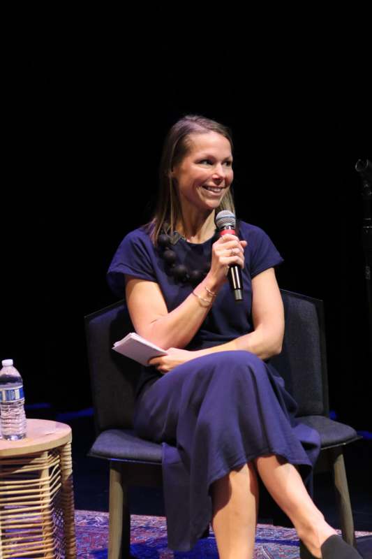 a woman sitting in a chair holding a microphone