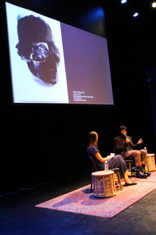 a man sitting in chairs and a woman sitting on a stage
